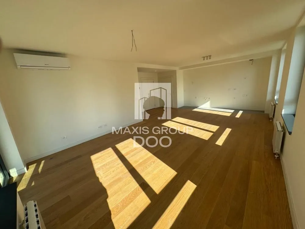 Empty living room with wooden flooring and an air conditioning unit.