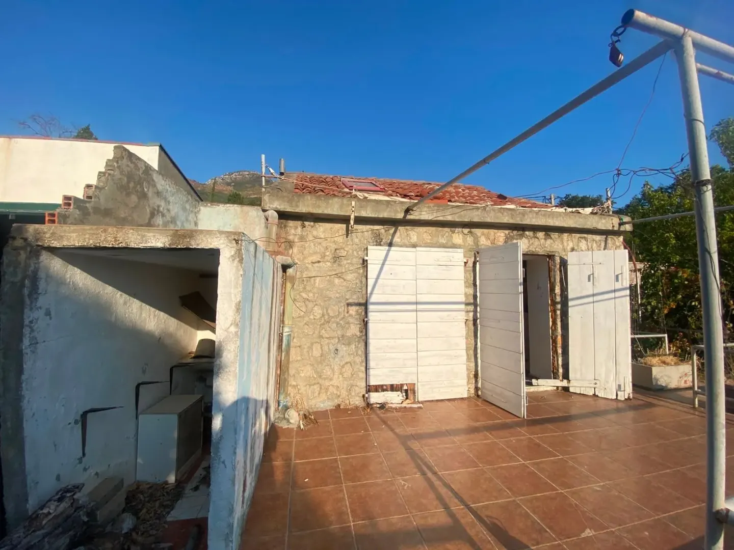 Pogled na spoljašnjost stare kamene kuće sa terasom.