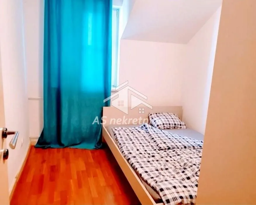 Smaller bedroom with a bed and turquoise curtains.