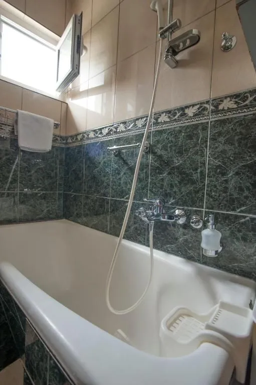 Small bathroom with a bathtub and green ceramic tiles.