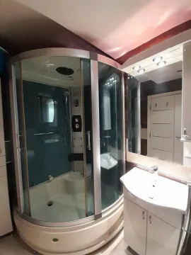 Bathroom equipped with a hydro-massage shower cabin and a vanity with a sink. - image 16
