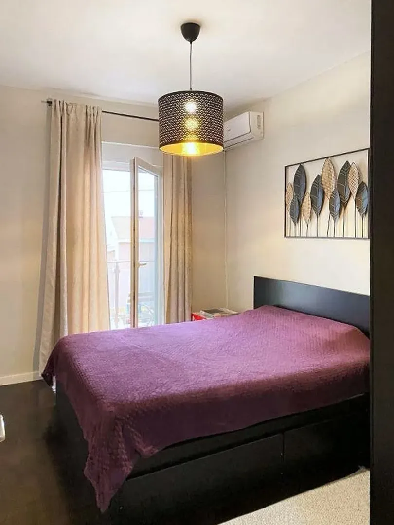 Namještena spavaća soba sa bračnim krevetom i izlazom na balkon.