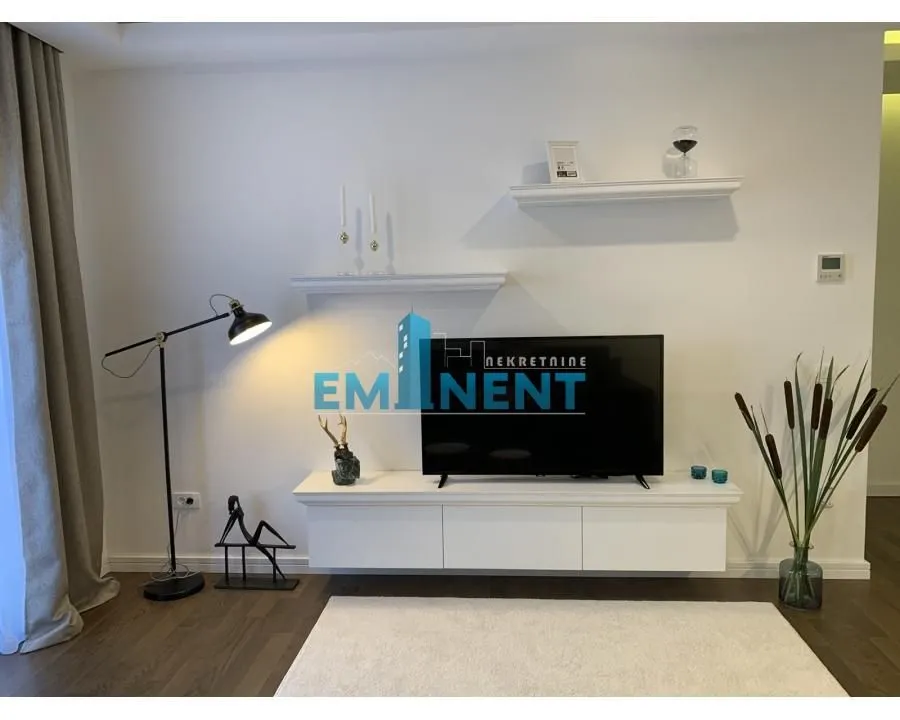Living room with a TV unit, shelves, and decorative lighting.