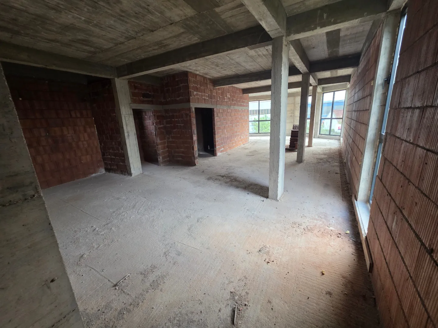 Unfinished interior of a building under construction with concrete pillars and brick walls.