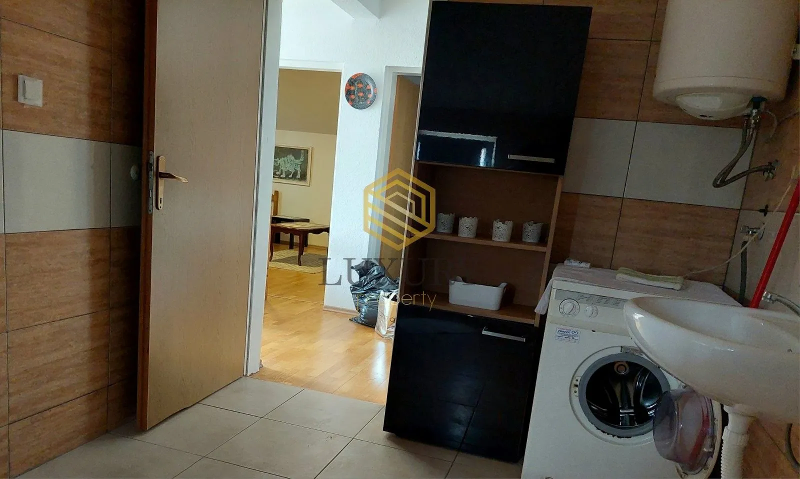 Small cluttered bathroom with a washing machine and a view of the hallway.