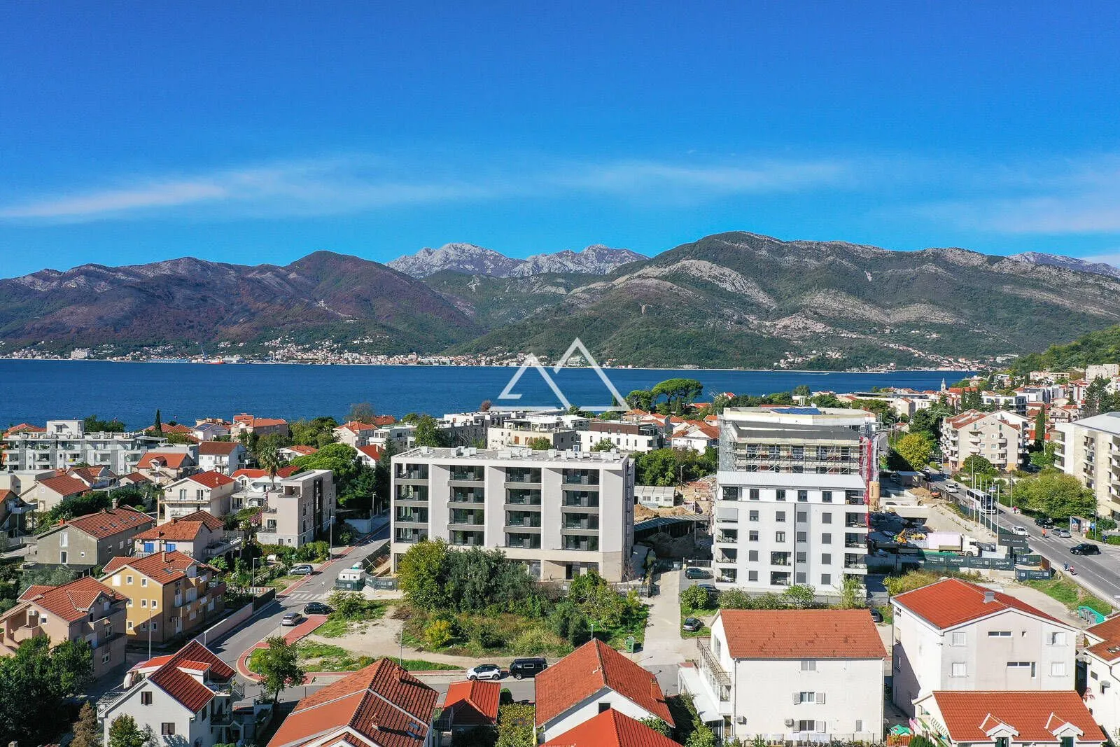 Pogled iz vazduha na naselje, more i planine u pozadini.