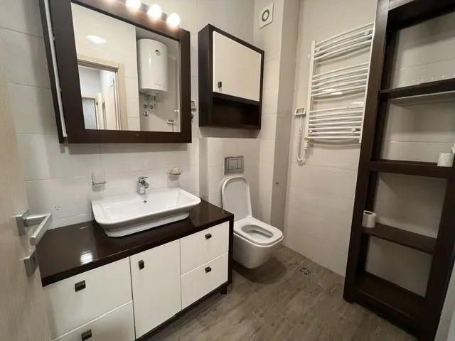 Moderno kupatilo sa bijelim sanitarijama i drvenim namještajem.