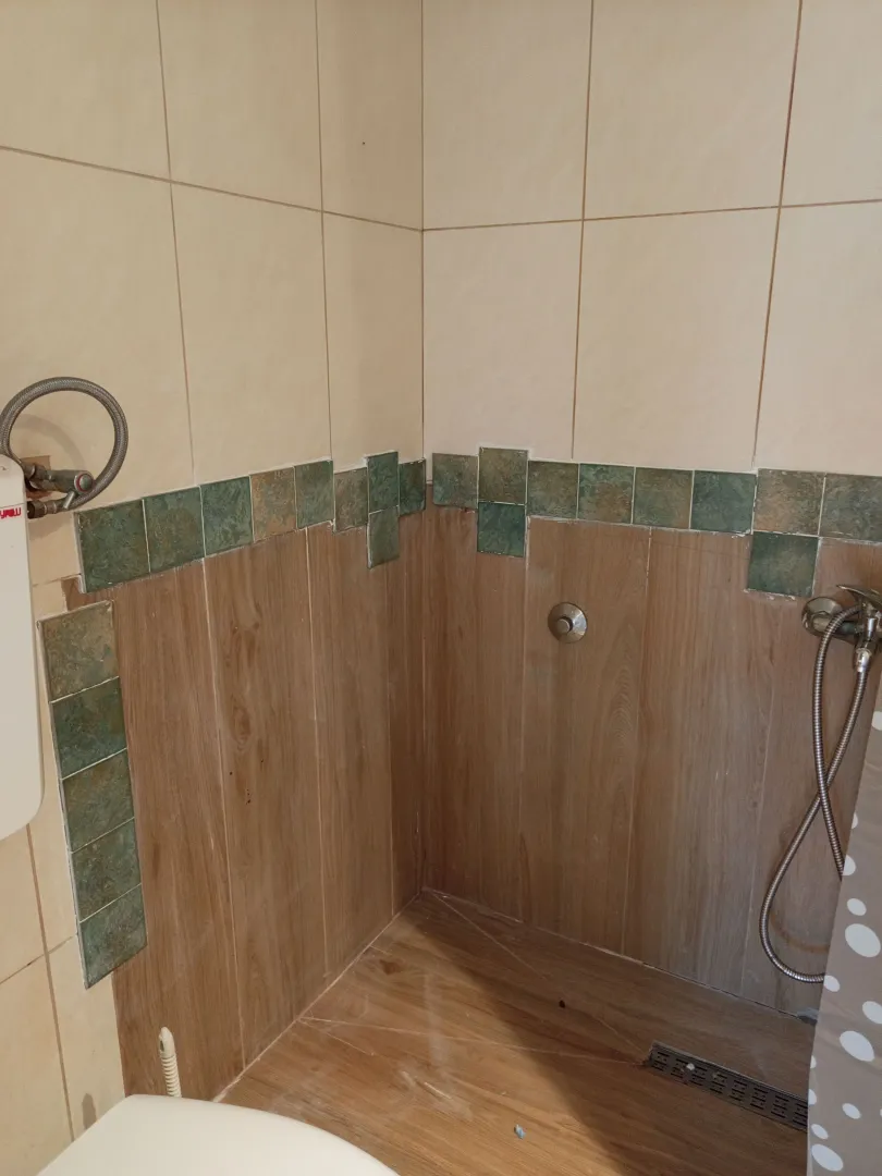 Pogled na dio kupatila sa tuš kabinom i keramičkim pločicama.