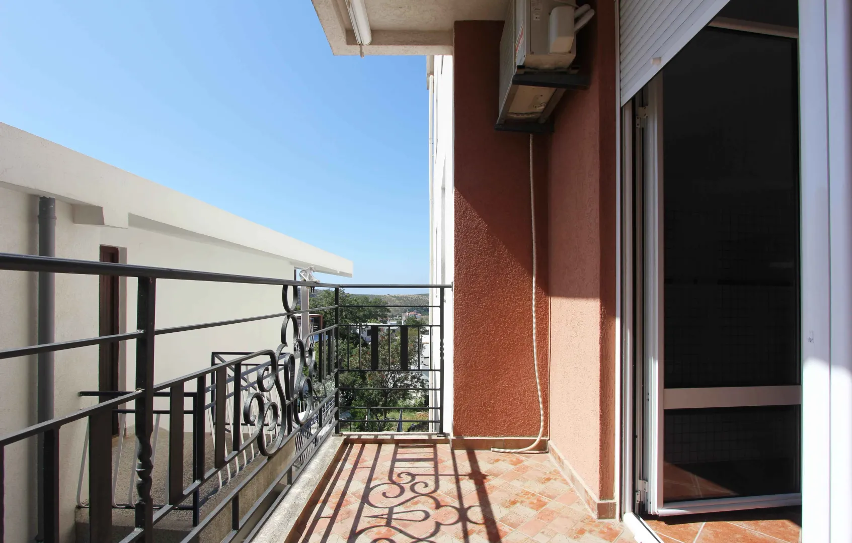 Balkon sa metalnom ogradom i pogledom na okolinu.