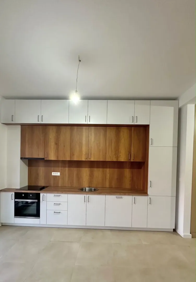 Moderna kuhinja sa bijelim i drvenim elementima.