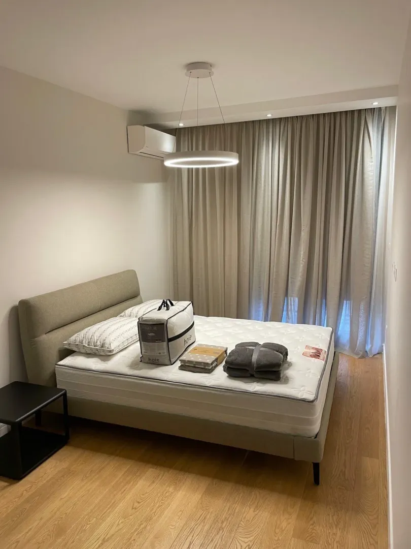 Svijetla spavaća soba sa modernim osvjetljenjem i novim krevetom.