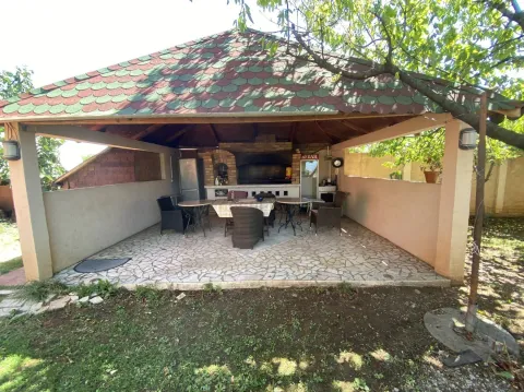 A covered garden pavilion with a barbecue grill and seating area. - image 8