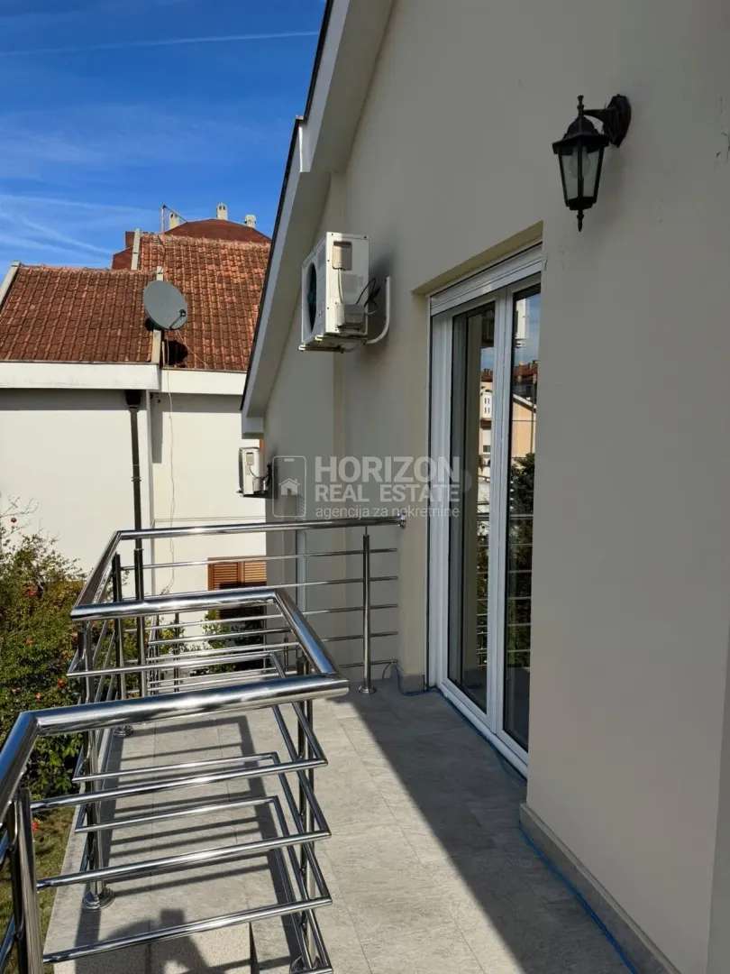 Spacious balcony with metal railing and access to the yard.