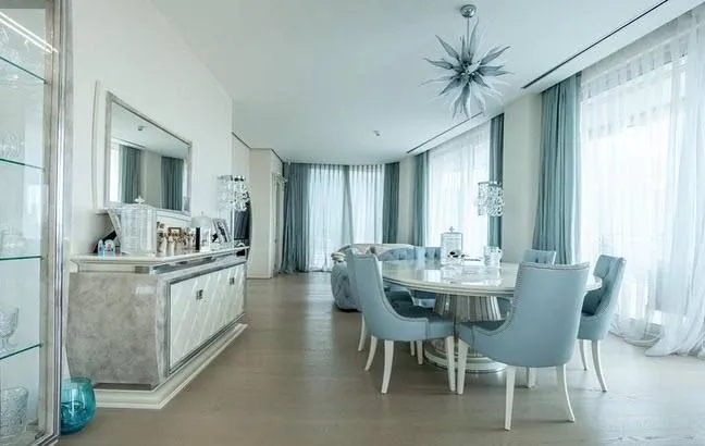 Spacious and bright living room with a dining area, elegant furniture, and large windows.
