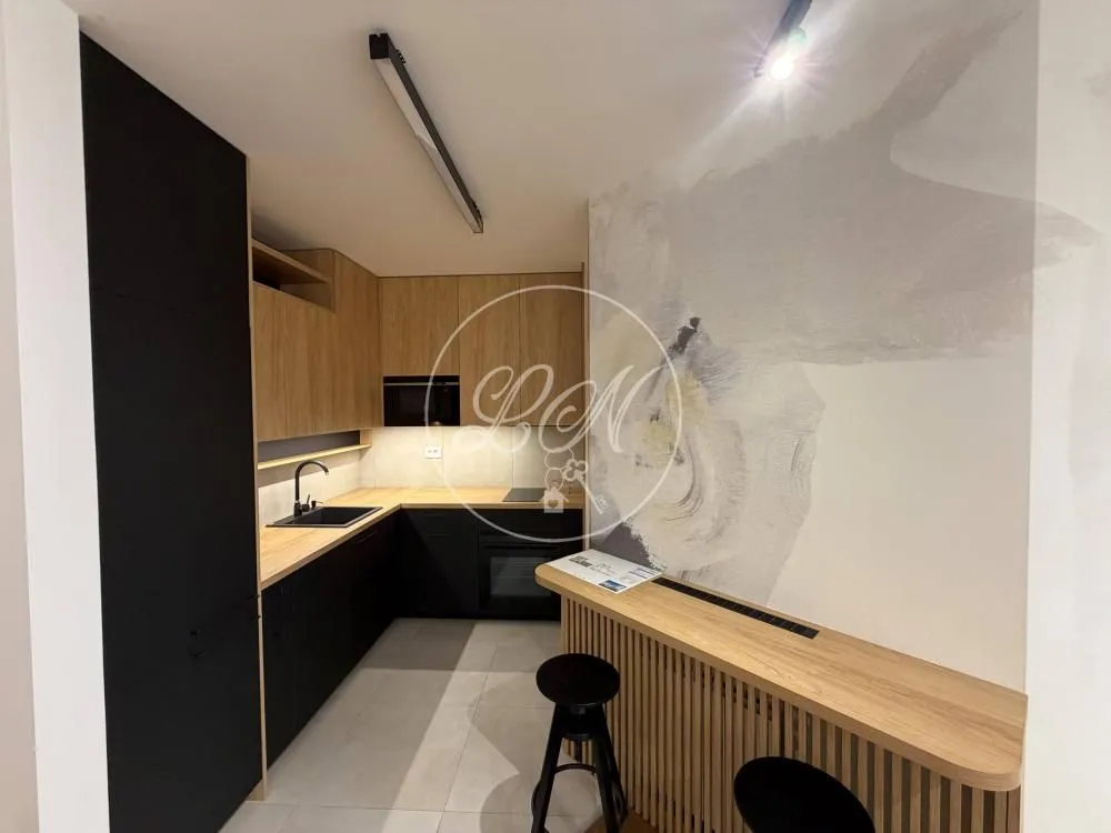 Modern kitchen with dark cabinetry and a wooden breakfast bar with bar stools.
