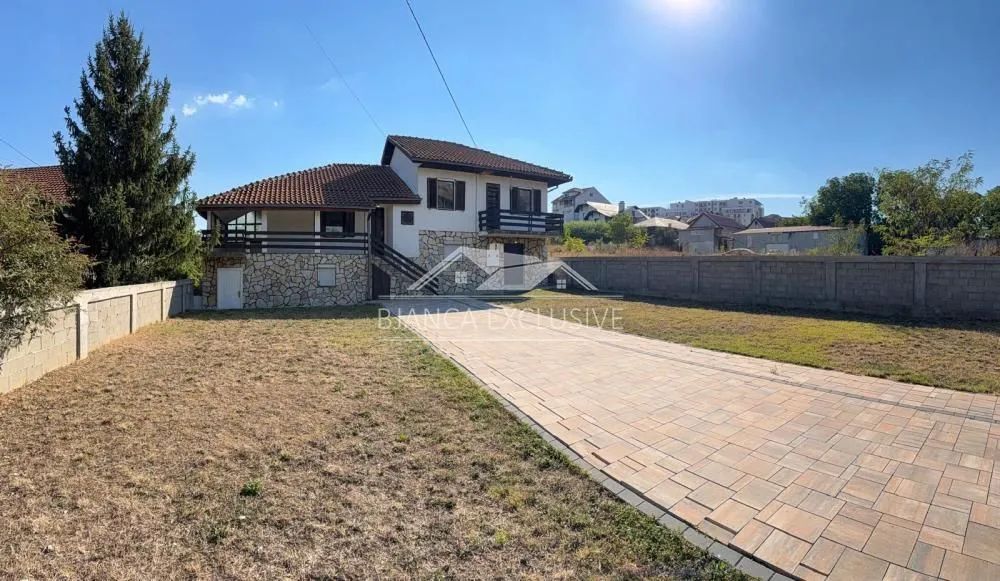 Spoljašnji izgled kuće sa dvorištem i popločanim prilazom.