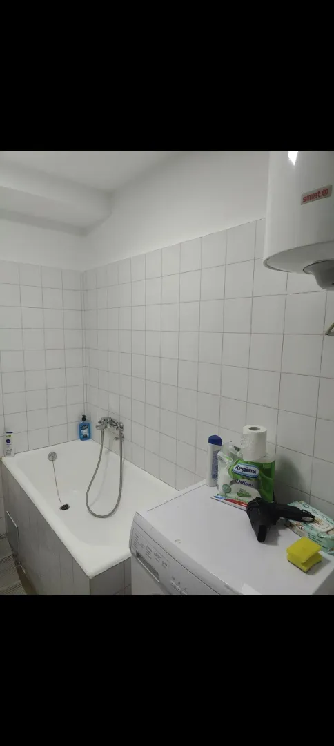 Manje kupatilo sa kadom, bijelim pločicama i mašinom za veš.