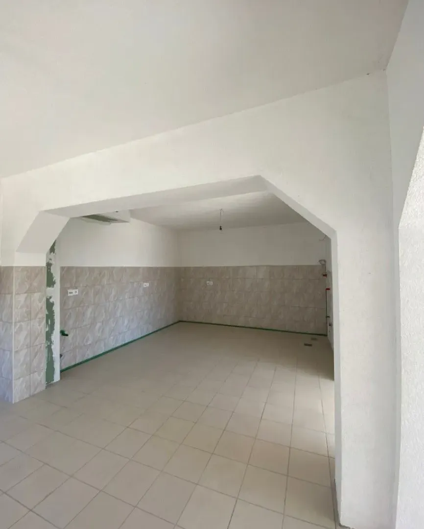 Empty room with tiled floors and walls, prepared for a kitchen.