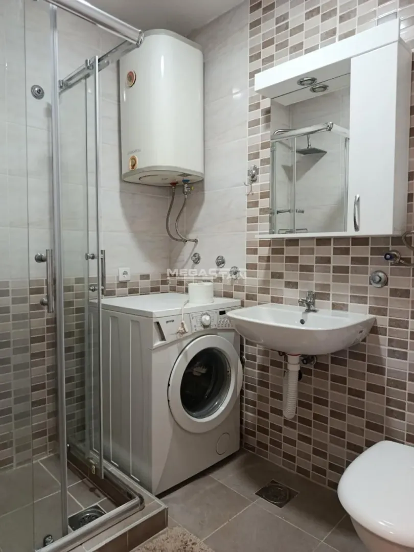 Kompaktno kupatilo sa tuš kabinom, umivaonikom, veš mašinom i bojlerom.