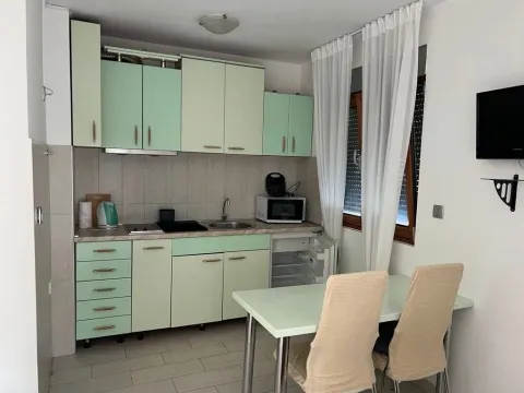Small kitchen with green cabinets and a dining table with chairs. - image 2