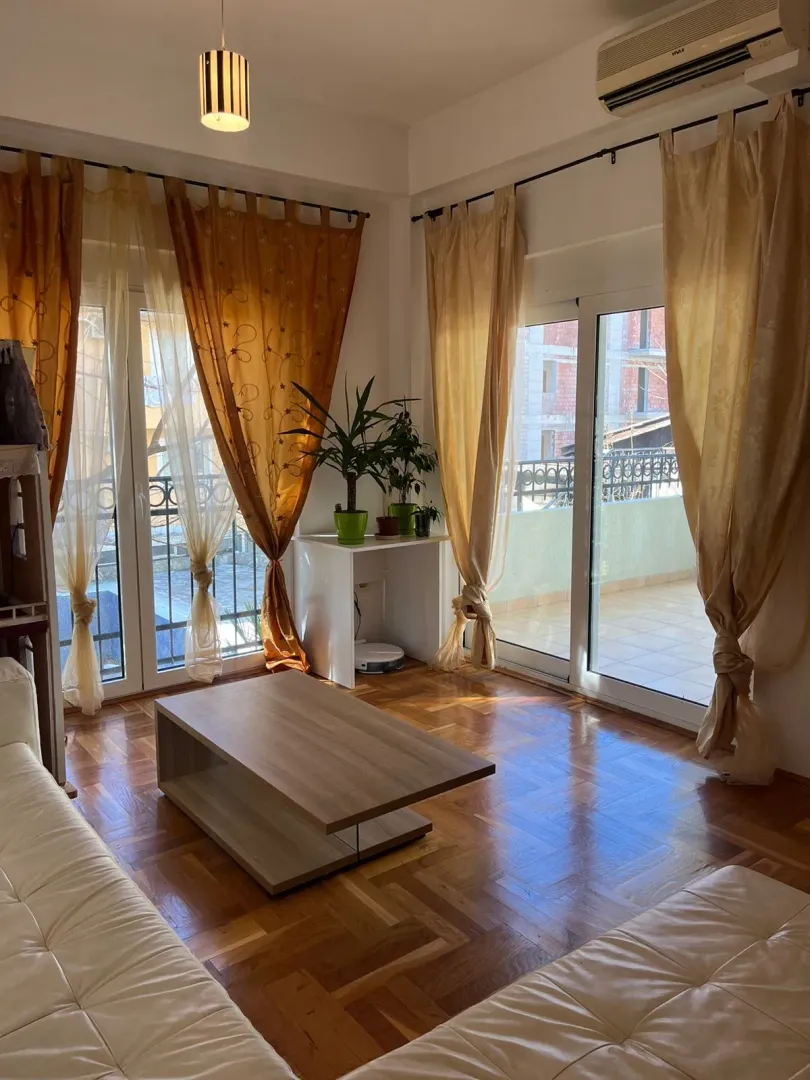 Living room with parquet flooring, sofa set, and access to the terrace.