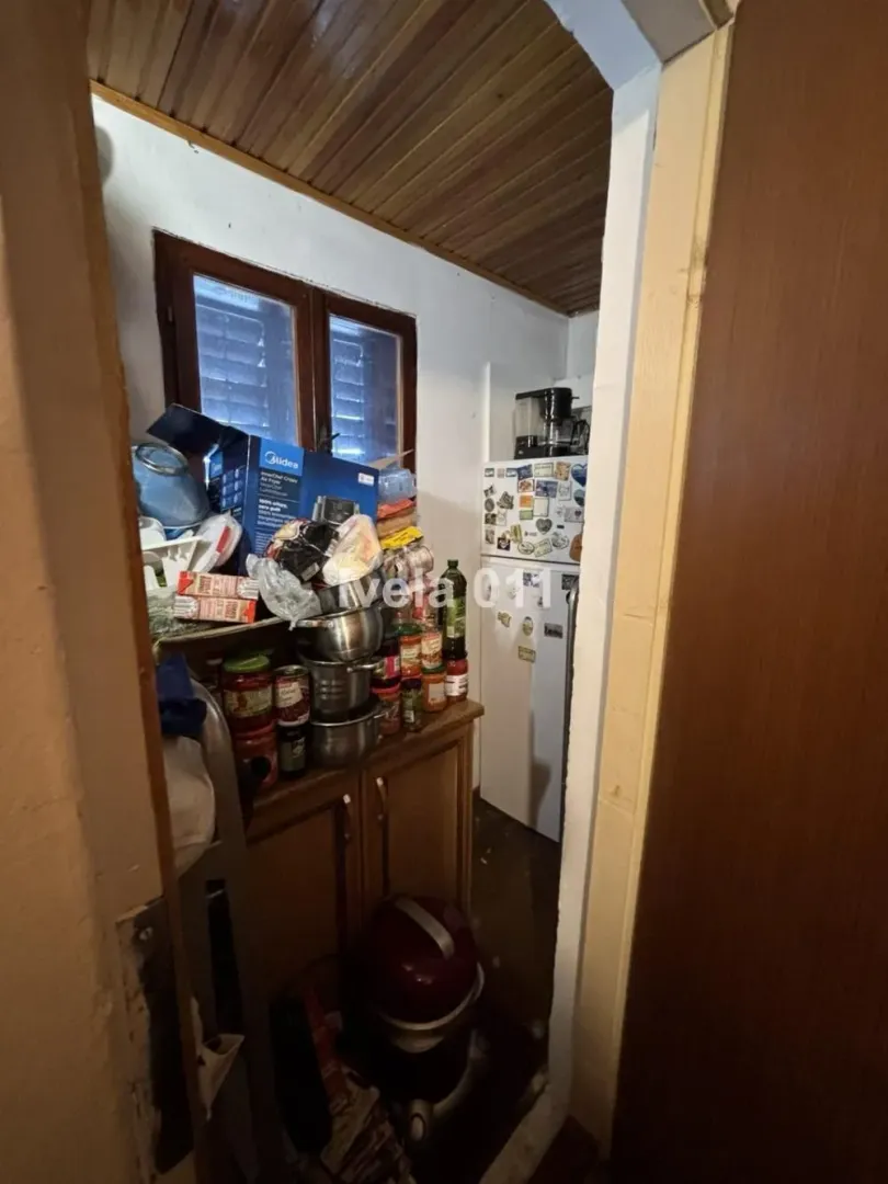 Small kitchen with a refrigerator, cabinets, and stored food items.