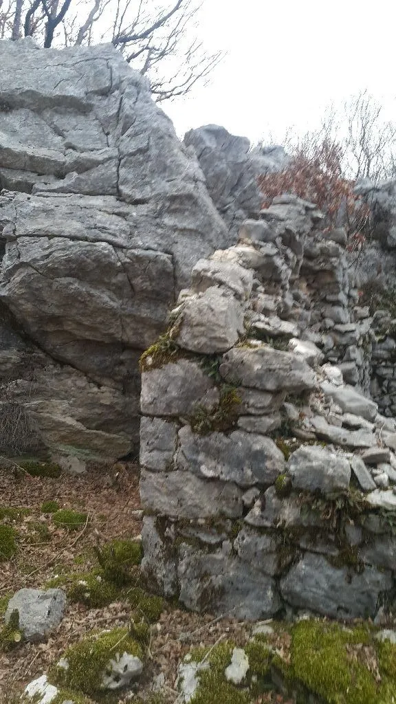 Ruševni kameni zid u prirodnom okruženju sa stijenama.