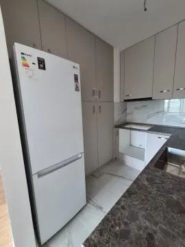 Moderna kuhinja sa ugradnim elementima i belim frižiderom. - image 4