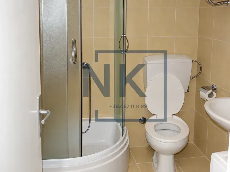 Compact bathroom with a shower cabin, toilet, and sink.