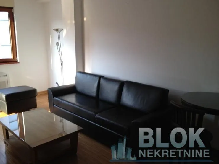 Living room with a black leather sofa set and a wooden coffee table.