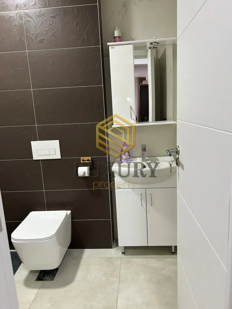 Manje kupatilo sa WC šoljom i umivaonikom sa ormarićem.