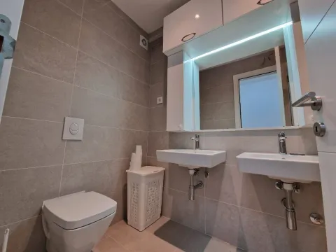Modern bathroom with two sinks, a toilet, and an illuminated mirror. - image 7