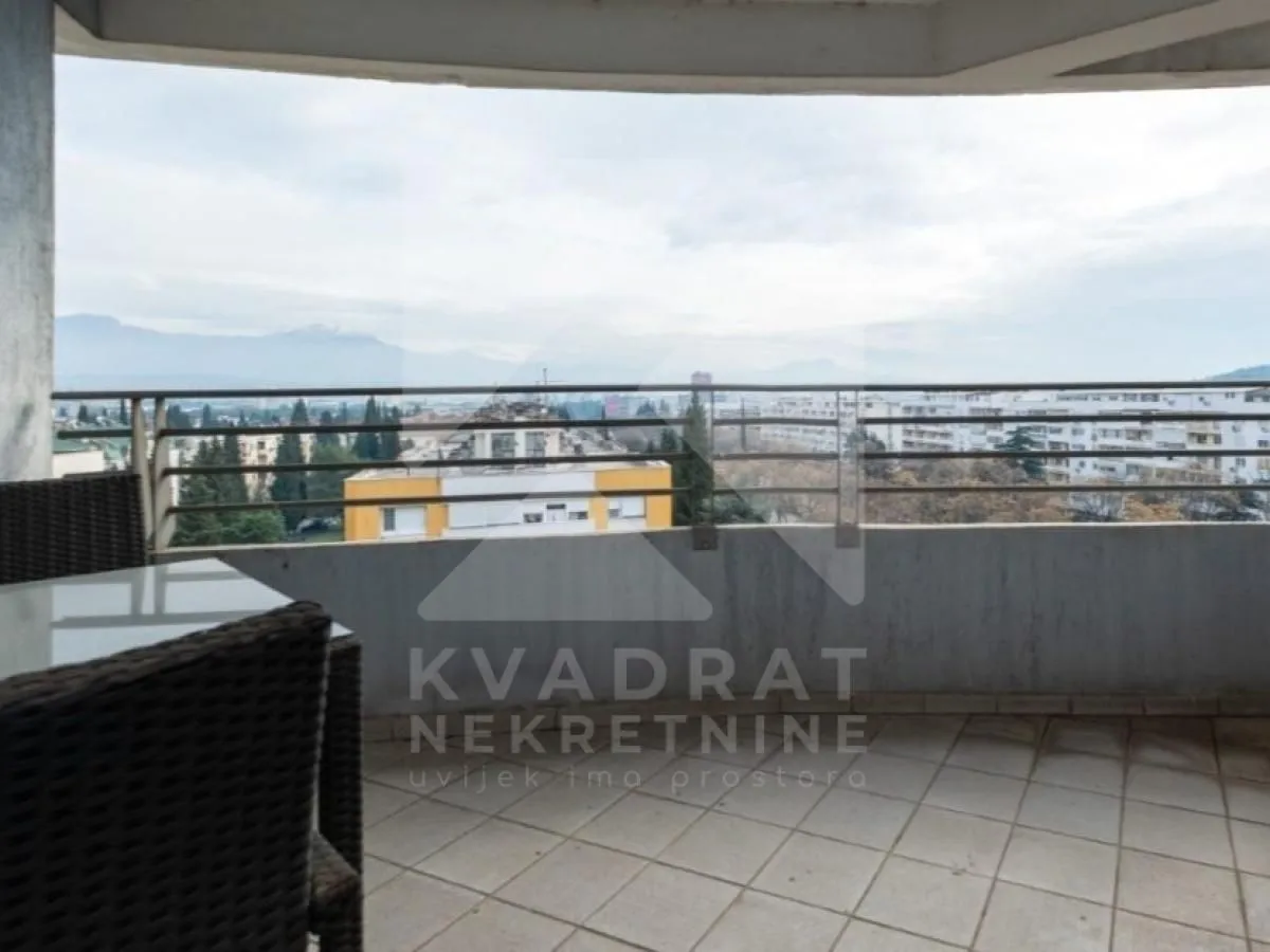 Natkrivena terasa sa pogledom na grad i okolne planine.