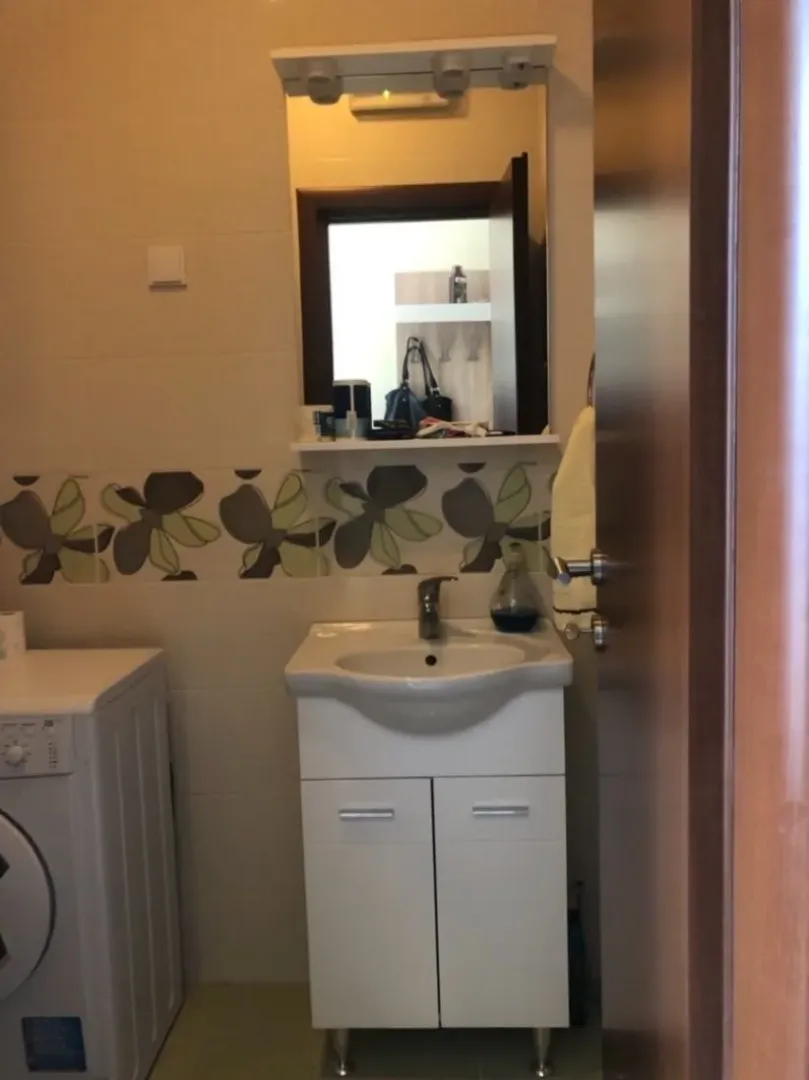 A bathroom featuring a sink, mirror, and washing machine.