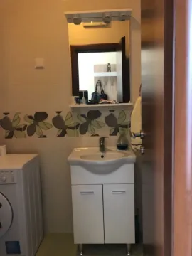A bathroom featuring a sink, mirror, and washing machine. - image 11