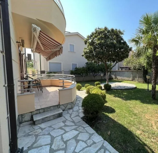 House yard with a paved path, terrace, and landscaped lawn.