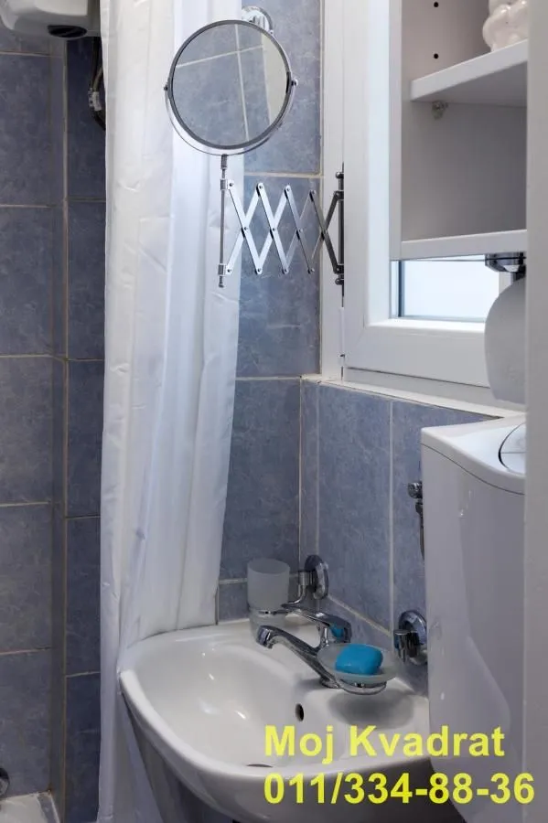 Small bathroom with a sink and shower stall tiled with blue tiles.