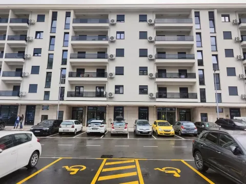 Exterior view of a modern multi-family residential building with a parking lot in the foreground. - image 4