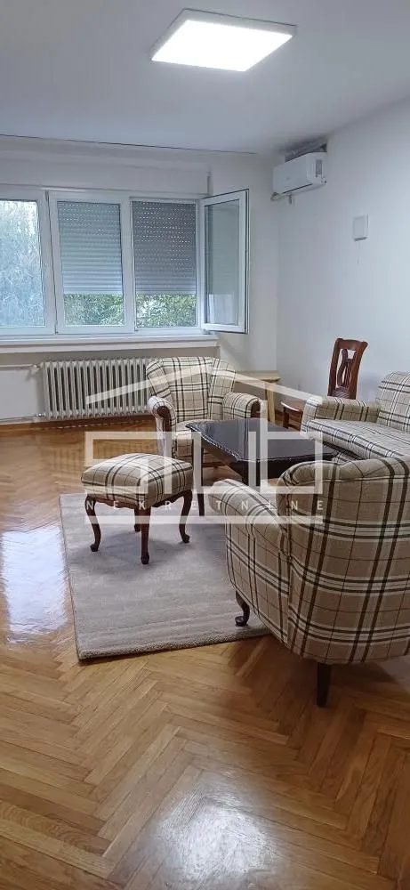Living room with seating furniture and parquet flooring.