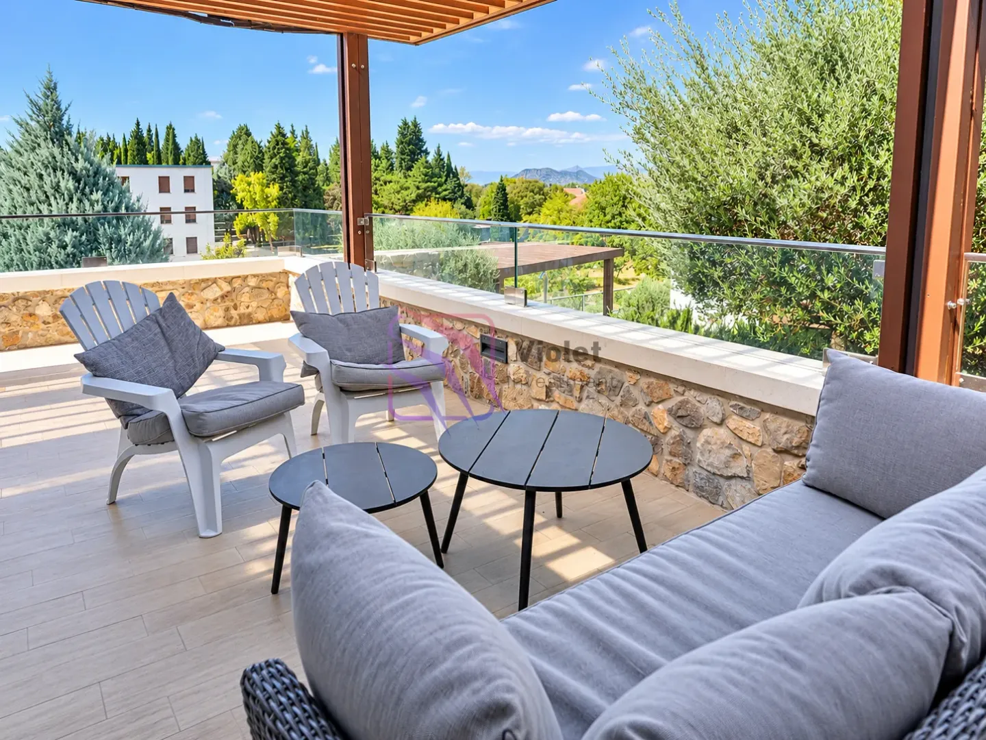 Spacious terrace with seating furniture and a view of greenery.