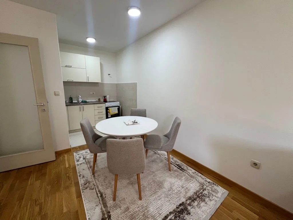 Dining area with a table and four chairs and a part of the kitchen in the background.