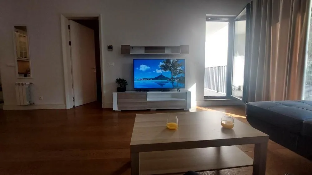 Living room with a TV, a wooden coffee table, and access to the terrace.
