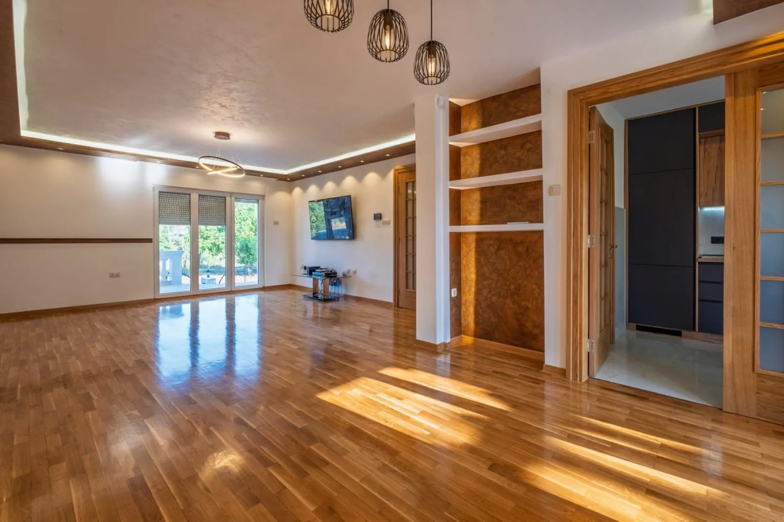 Spacious living room with wooden flooring and a dropped ceiling with lighting.