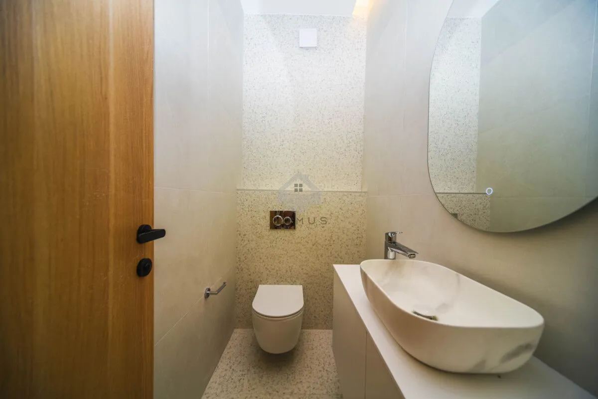 Modernly equipped bathroom with a washbasin, mirror, and toilet.