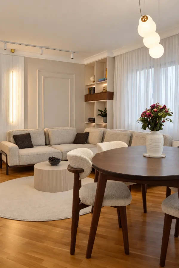 Dnevna soba sa ugaonom garniturom, trpezarijskim stolom i modernim osvetljenjem.