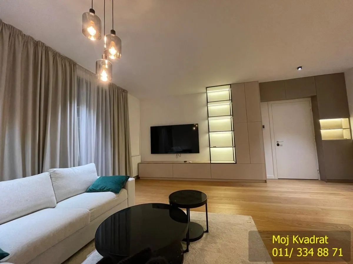 Living room with a sofa, TV, and modern lighting.