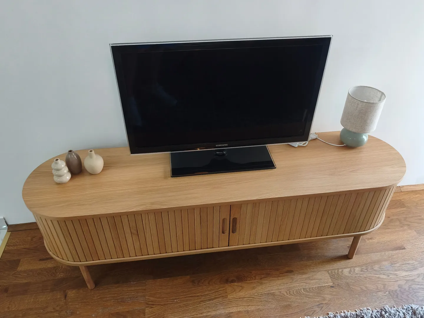 Wooden TV unit with a television and decorative vases.