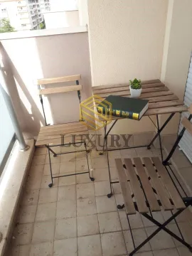 Manji namješteni balkonski prostor sa drvenim stolom i dvije stolice. - image 4