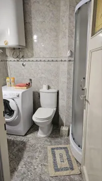 Bathroom equipped with a shower cabin, toilet, washing machine, and water heater. - image 12