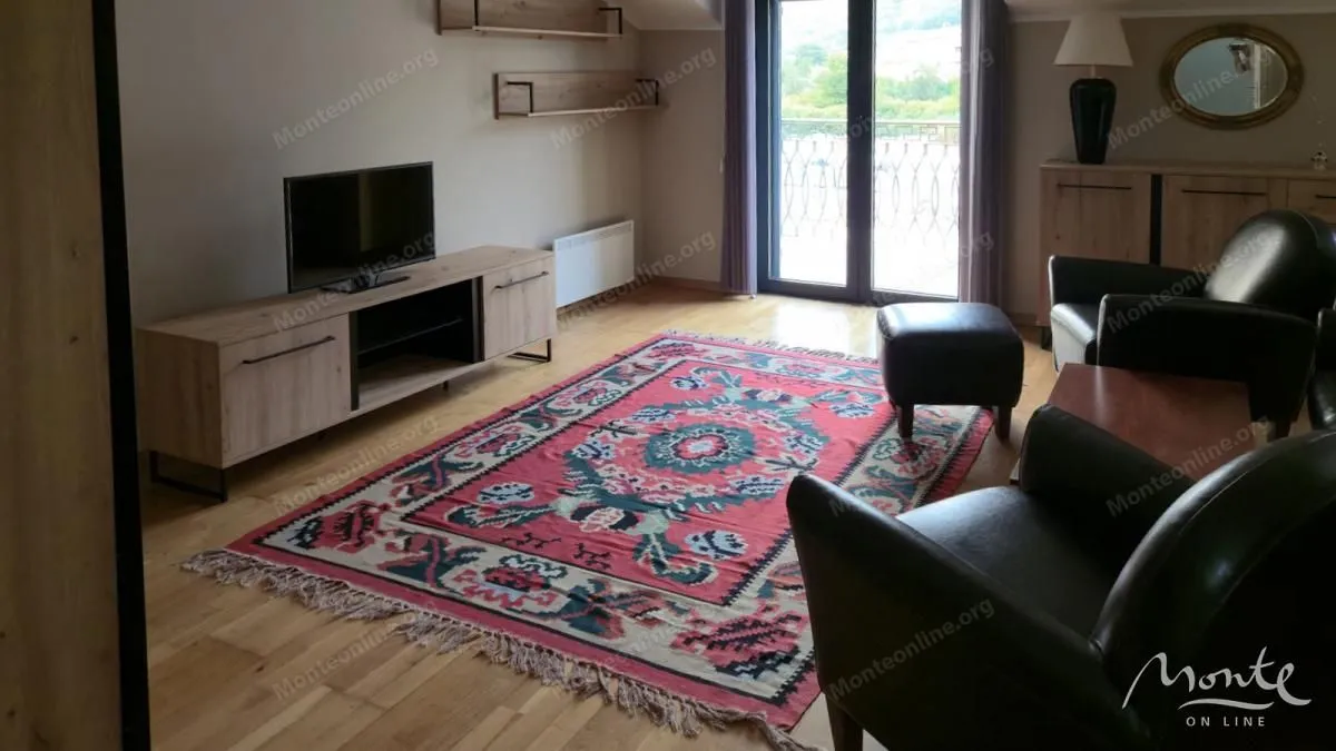 Dnevna soba sa garniturom, televizorom i tradicionalnim tepihom.
